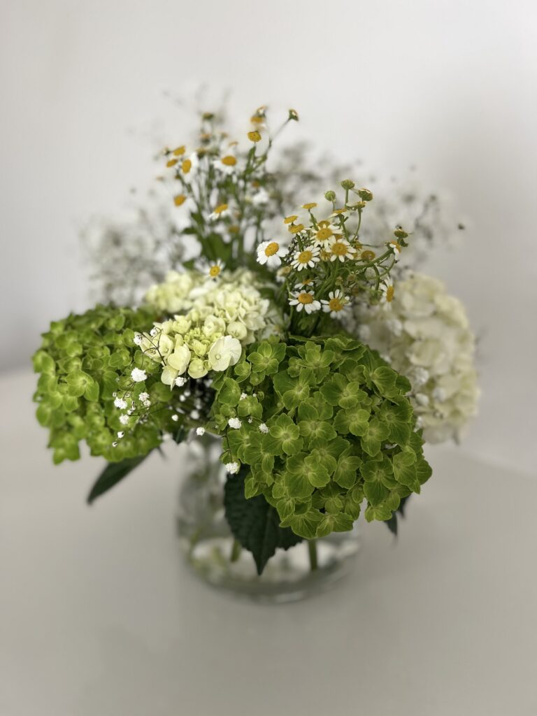 The arrangement you will be creating: hydrangeas, baby's breath, and chamomile in a glass vase