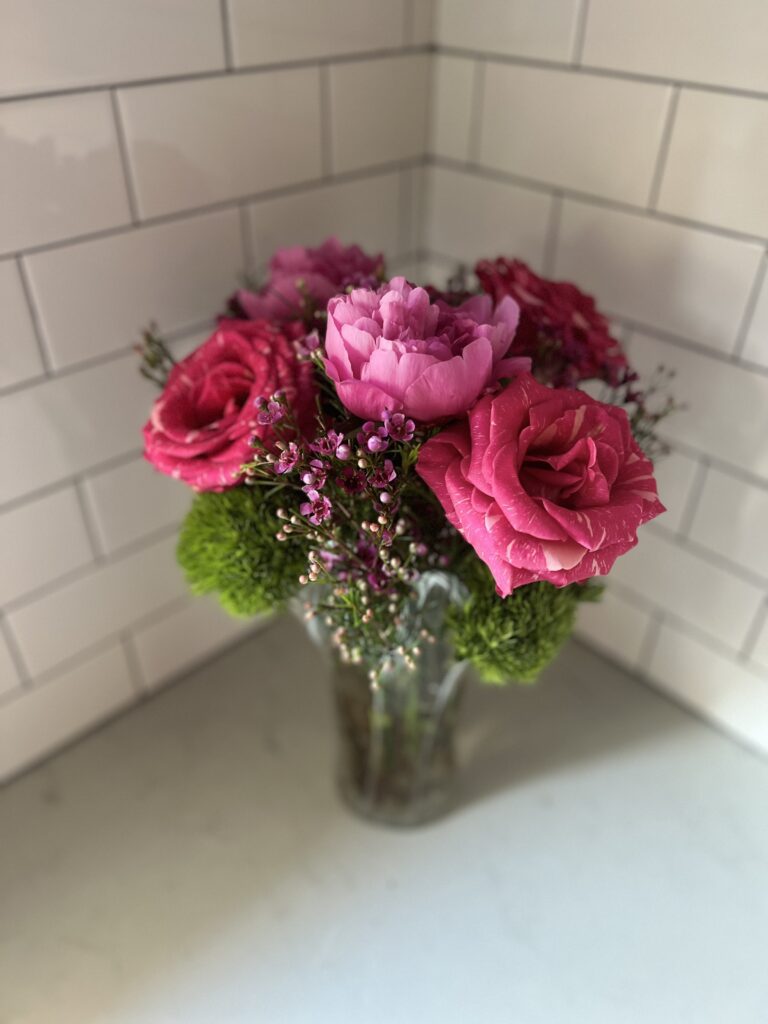 The arrangement you will be creating: striped pink roses, peonies, green ball dianthus, and waxflower in a tall glass vase